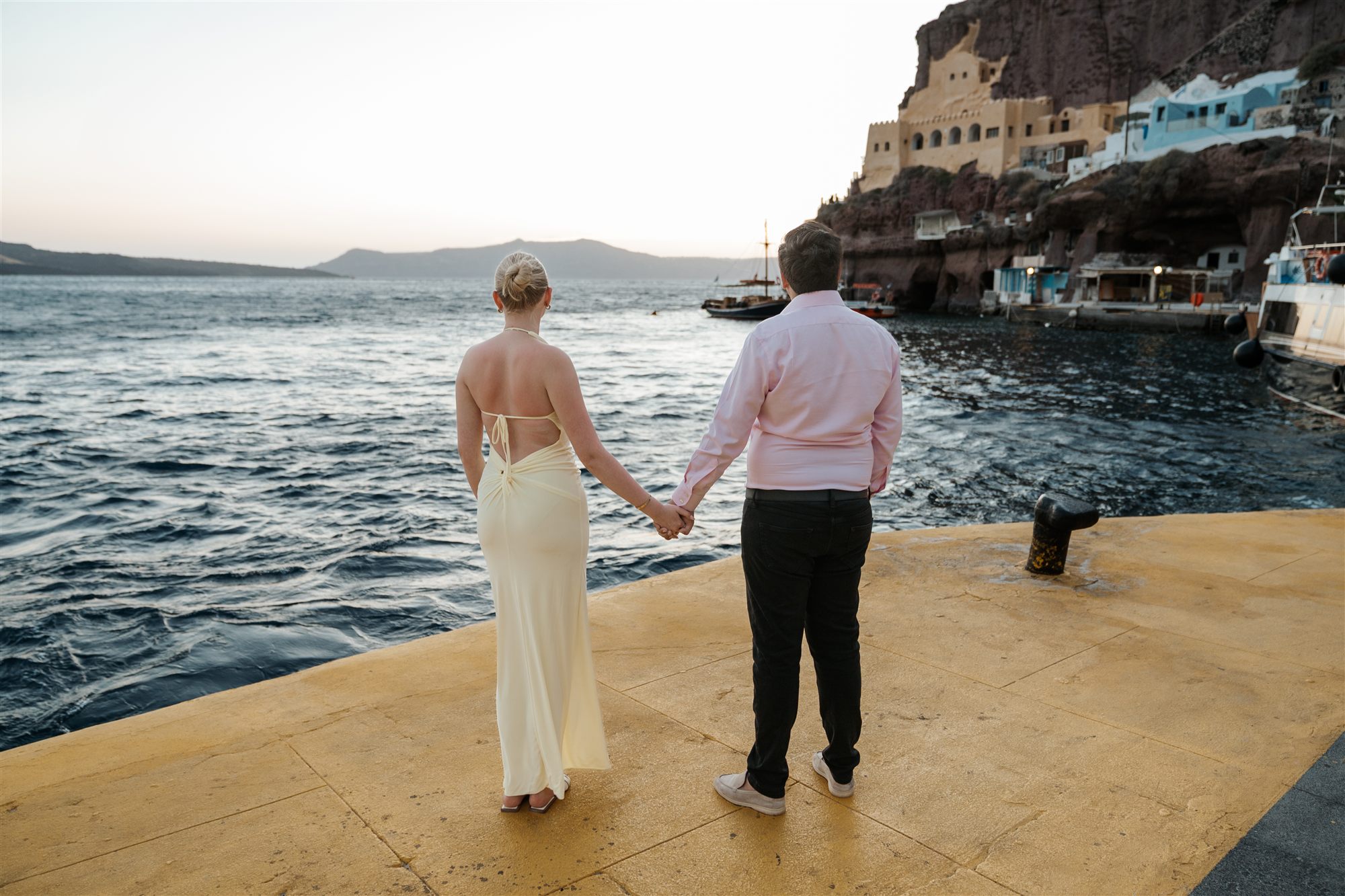Marco and Lilly holding hands at the old port of Fira under the caldera cliffs