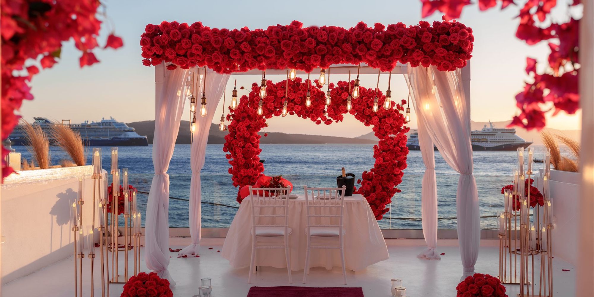 red rose canopy and private dinner table at sunset - Santorini proposal setup